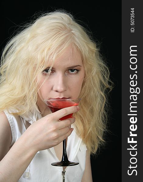 Young blond woman holds martini against the black background. Young blond woman holds martini against the black background