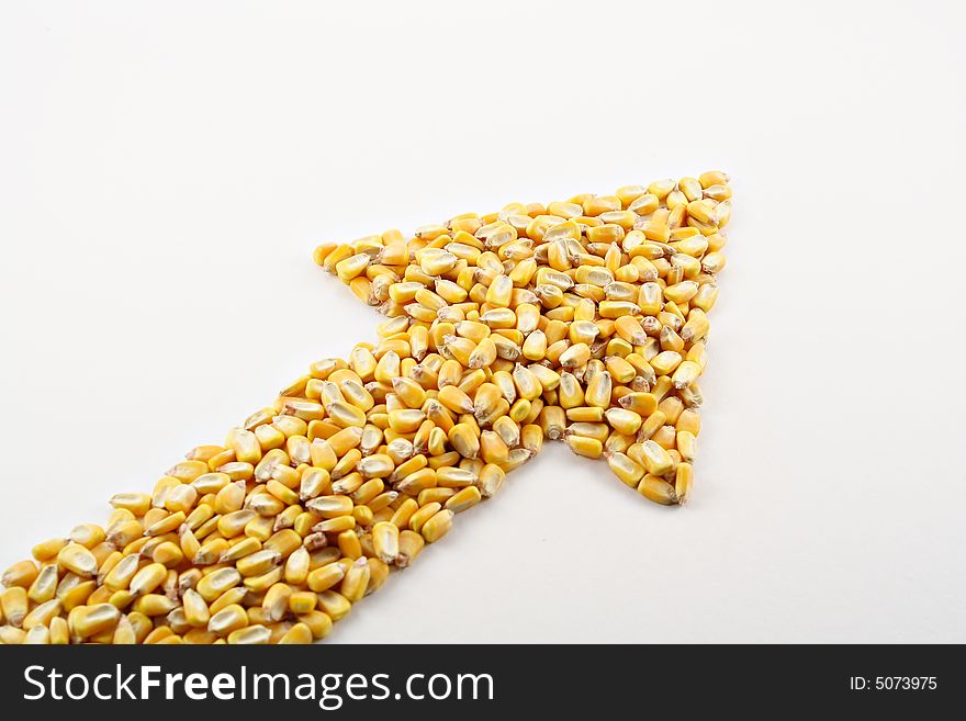 A pile of corn kernels arranged into an up arrow to reflect the high price of corn. A pile of corn kernels arranged into an up arrow to reflect the high price of corn