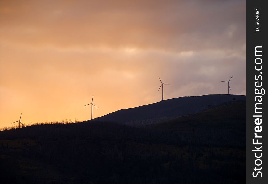 Wind turbines generating energy on a hill at sunset