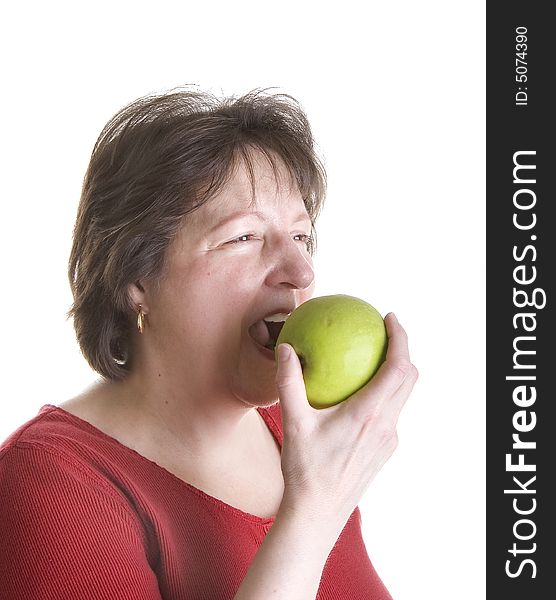 An attractive middle aged woman wearing a red blouse and eating a green apple. An attractive middle aged woman wearing a red blouse and eating a green apple