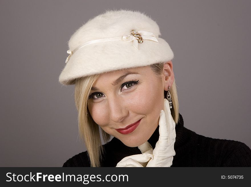 A blonde in a black turtleneck and a white fur hat wearing white gloves. A blonde in a black turtleneck and a white fur hat wearing white gloves