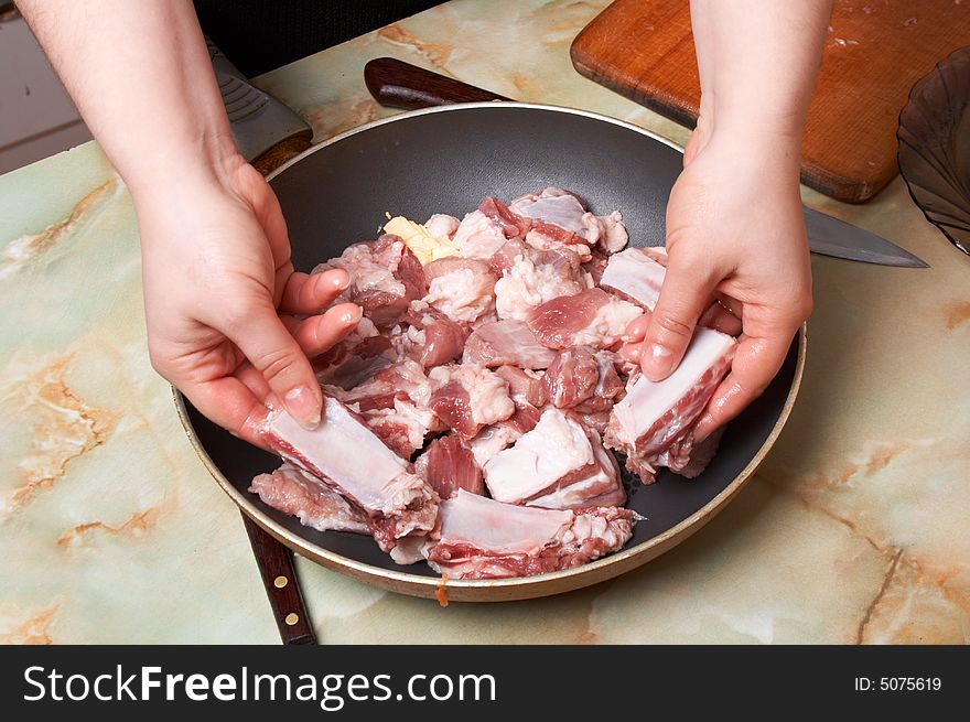 Placing meat pieces in frying pan.