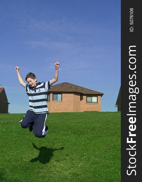 Happy teenager jumping, suburbs in the background