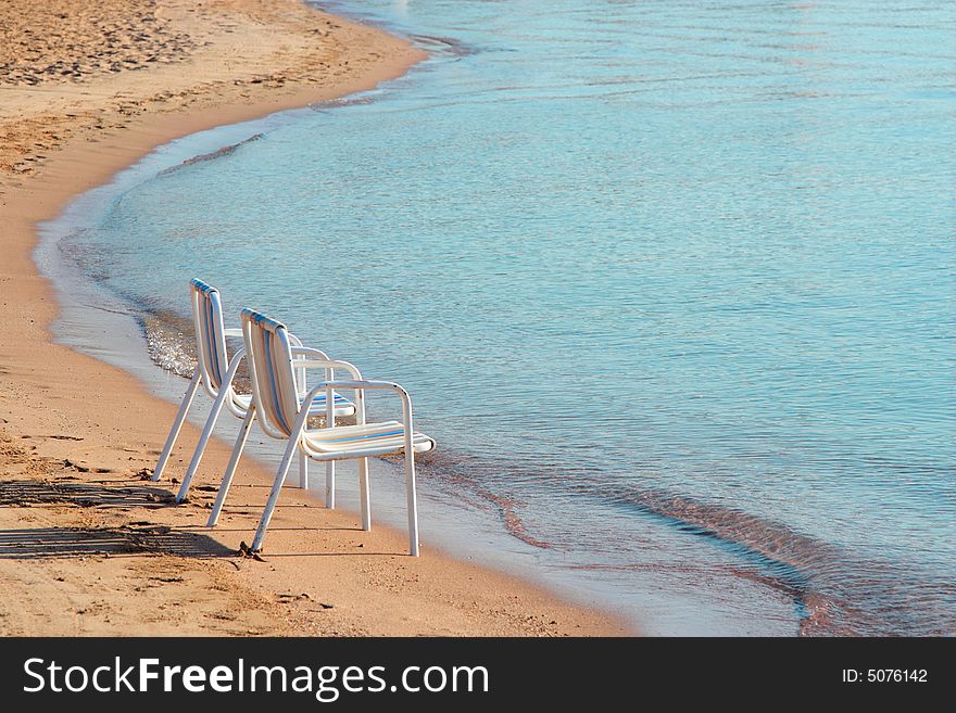 Two empty beach chairs on a lonely quite beach early in the morning. The location is at Hurghada, Egypt. Two empty beach chairs on a lonely quite beach early in the morning. The location is at Hurghada, Egypt.