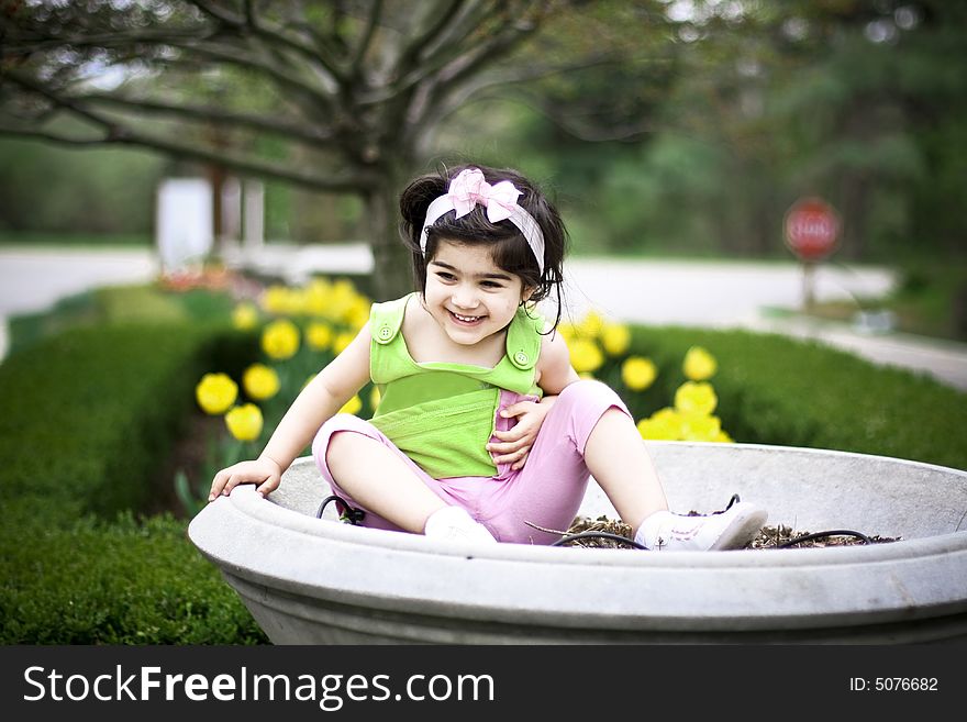 Girl in a pot laughing with flowers in the back