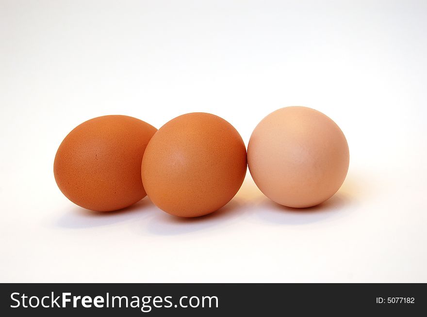 Three brown organic eggs on white background