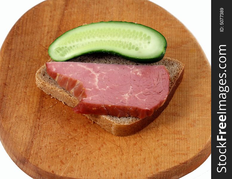Brisket with a cucumber on a kitchen board. Brisket with a cucumber on a kitchen board