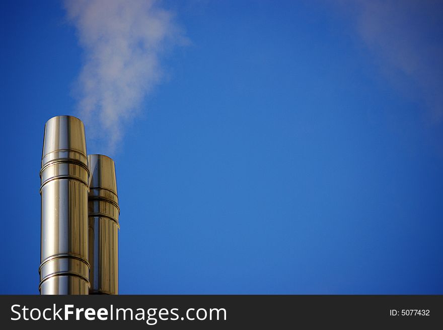 A cold chrome of chimneys against the blue sky in the morning. A cold chrome of chimneys against the blue sky in the morning