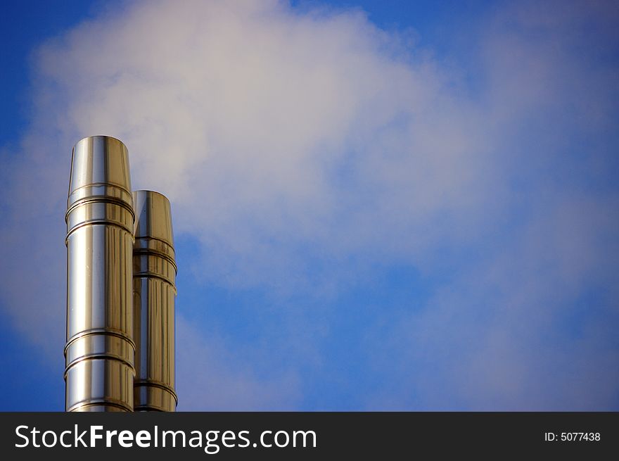 A cold chrome of chimneys with smoke against the blue sky in the morning. A cold chrome of chimneys with smoke against the blue sky in the morning