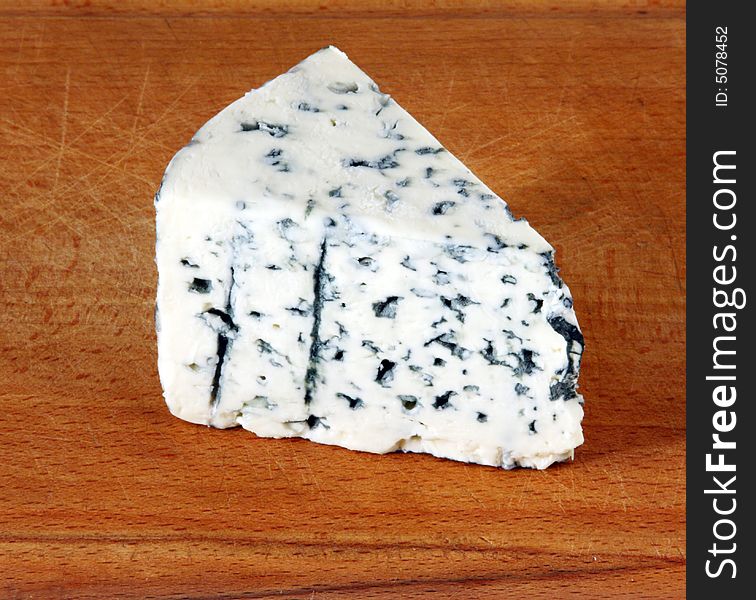 Ripe cheese with mould on a kitchen board