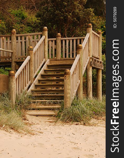 A set of timber steps leading down onto a sandy beach. A set of timber steps leading down onto a sandy beach
