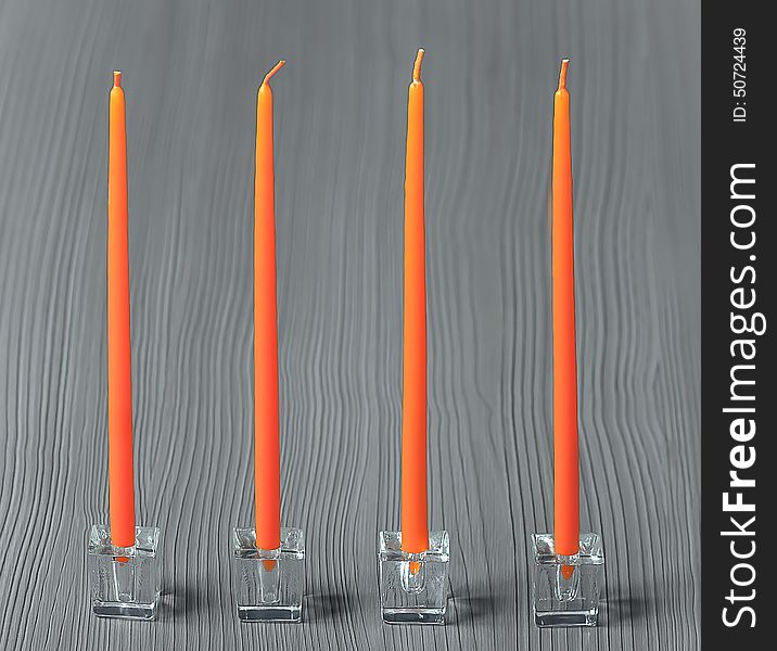 Set of four orange candles in transparent cubic plastic candlesticks on a grey textured wooden background. Set of four orange candles in transparent cubic plastic candlesticks on a grey textured wooden background.