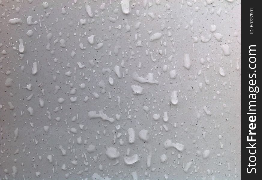 Clear water drops and black flecks on white smooth plastic or painted surface. Clear water drops and black flecks on white smooth plastic or painted surface.
