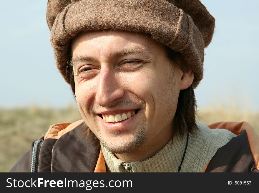 Portrait of happy man in hat on background of nature