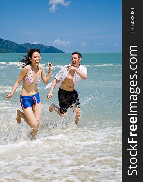 Young couple chasing and running on a beautiful tropical beach. Young couple chasing and running on a beautiful tropical beach