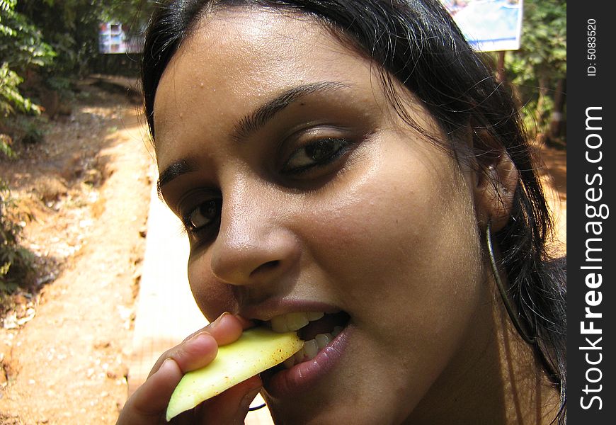 A girl eating fruit facing infront of the camera. A girl eating fruit facing infront of the camera