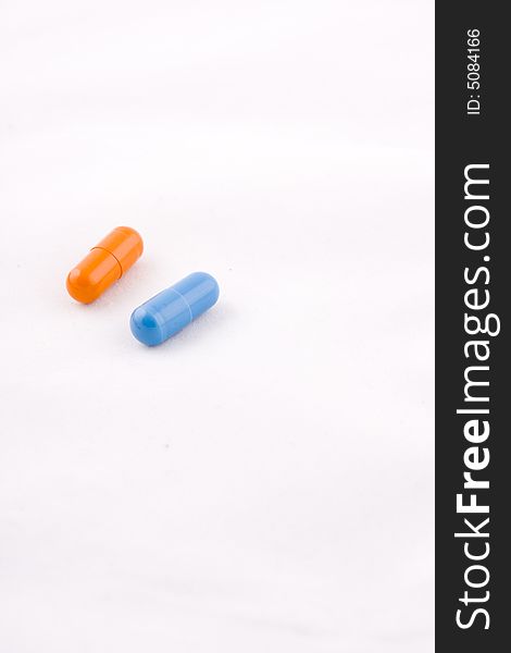 Pair of blue and orange pills, white background