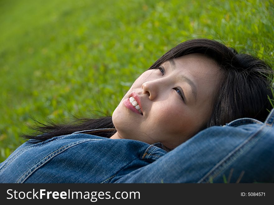 Dreams in the grass - young attractive woman  relaxes in the park