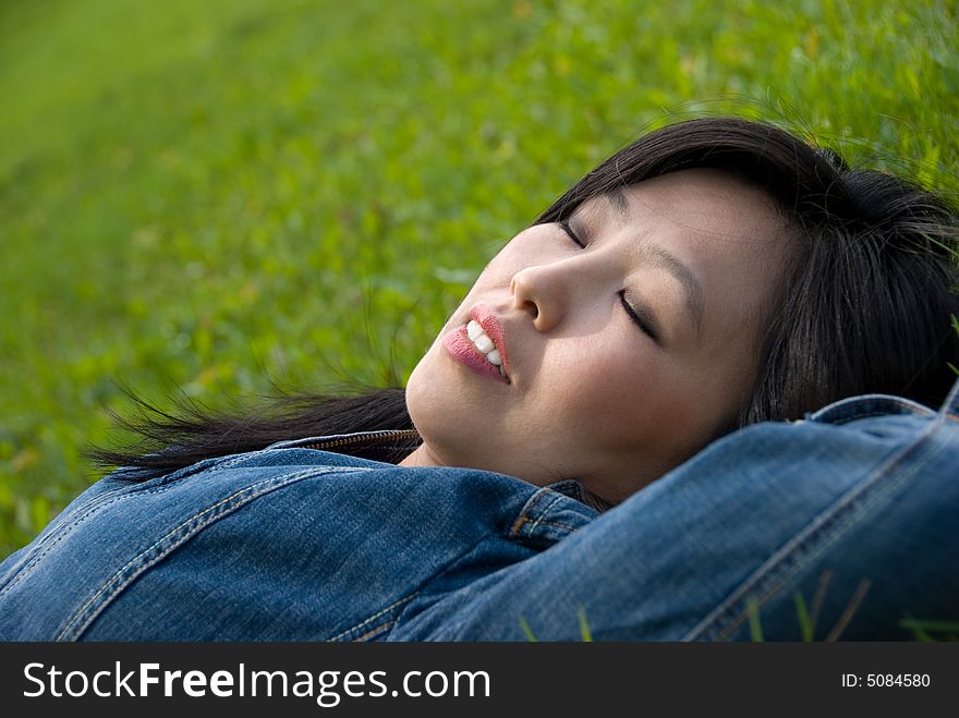 Dreams in the grass - young attractive woman relaxes in the park