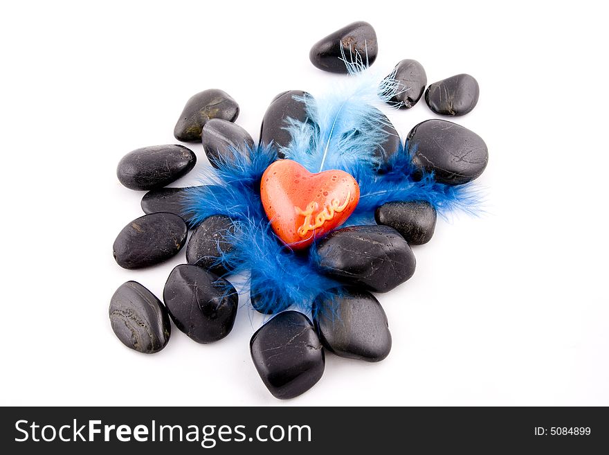 Red heart on black stones and blue plumage backrdound. Red heart on black stones and blue plumage backrdound