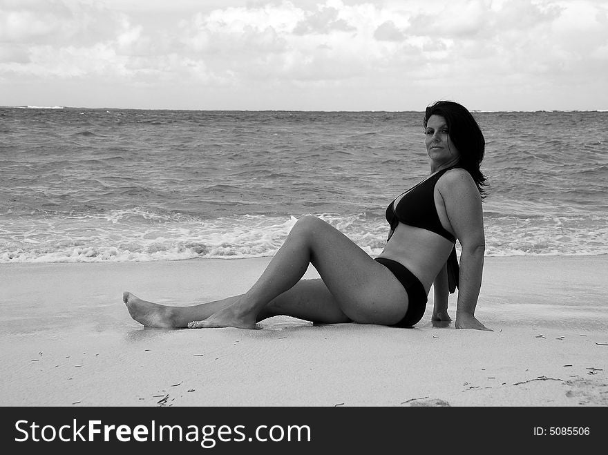 Beautiful, brunette swimsuit model in classic black and white posing on the white sands of the Caribbean.