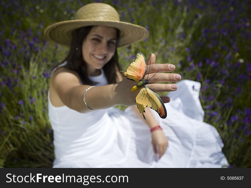Young girl in white dress sitting in the grass holding orange butterfly. Young girl in white dress sitting in the grass holding orange butterfly