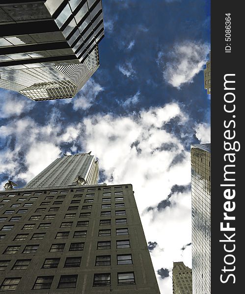 View of the city sky scrapers from below, with a cloudy blue sky. View of the city sky scrapers from below, with a cloudy blue sky.