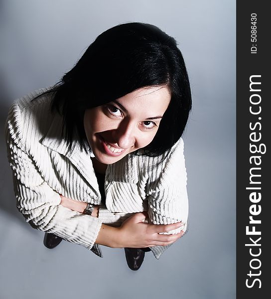 A high-key portrait about a young pretty lady with black hair who is looking up and she is smiling. She is wearing a white coat and a black dress. A high-key portrait about a young pretty lady with black hair who is looking up and she is smiling. She is wearing a white coat and a black dress.