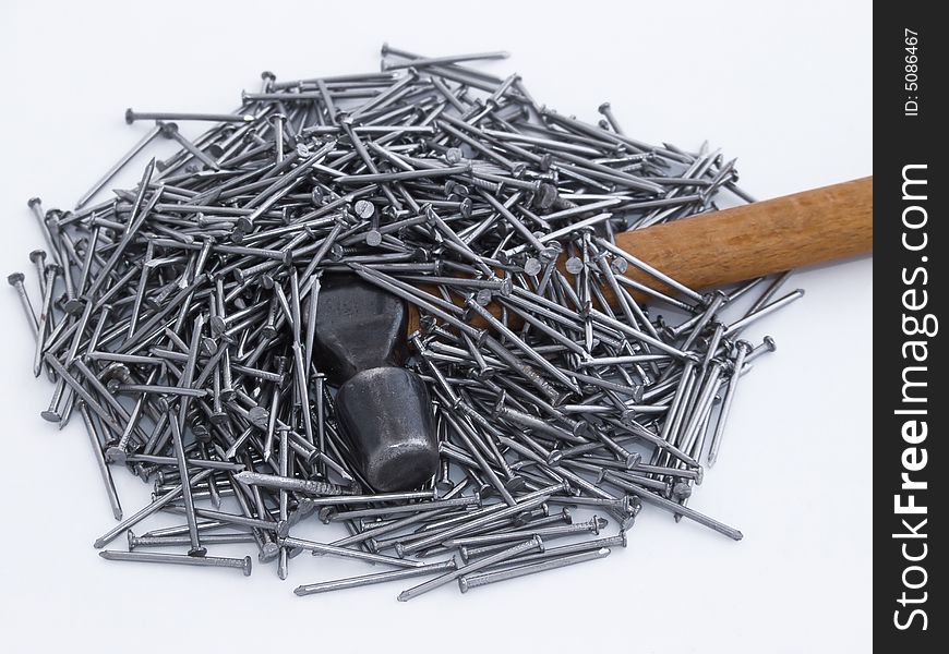 Iron hammer under stack of nails. Iron hammer under stack of nails