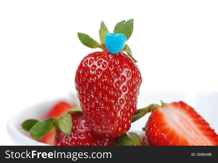 Close up to fresh strawberry with blue heart shaped toothpick