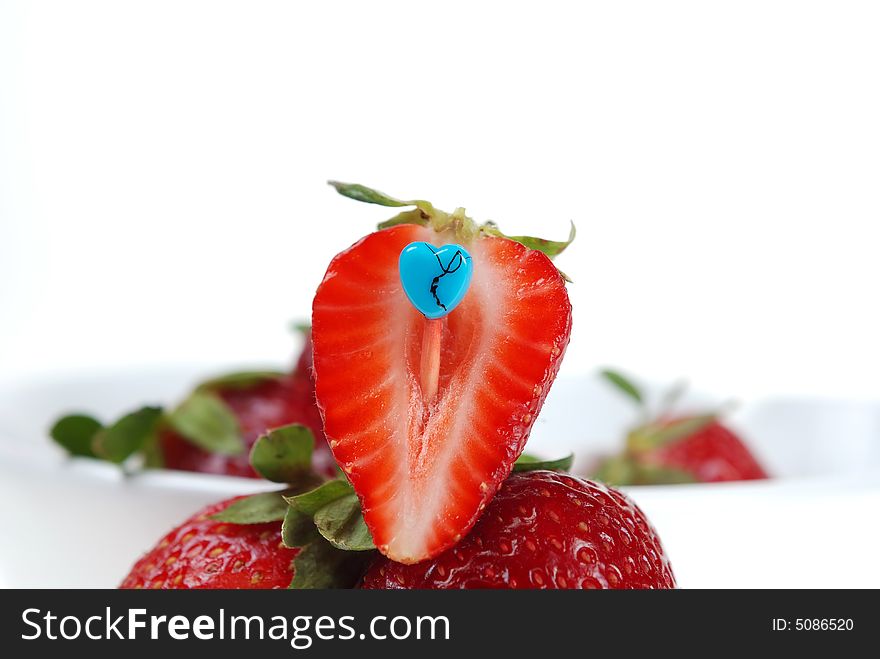 Close up to cut fresh strawberry with blue heart shaped toothpick. Close up to cut fresh strawberry with blue heart shaped toothpick