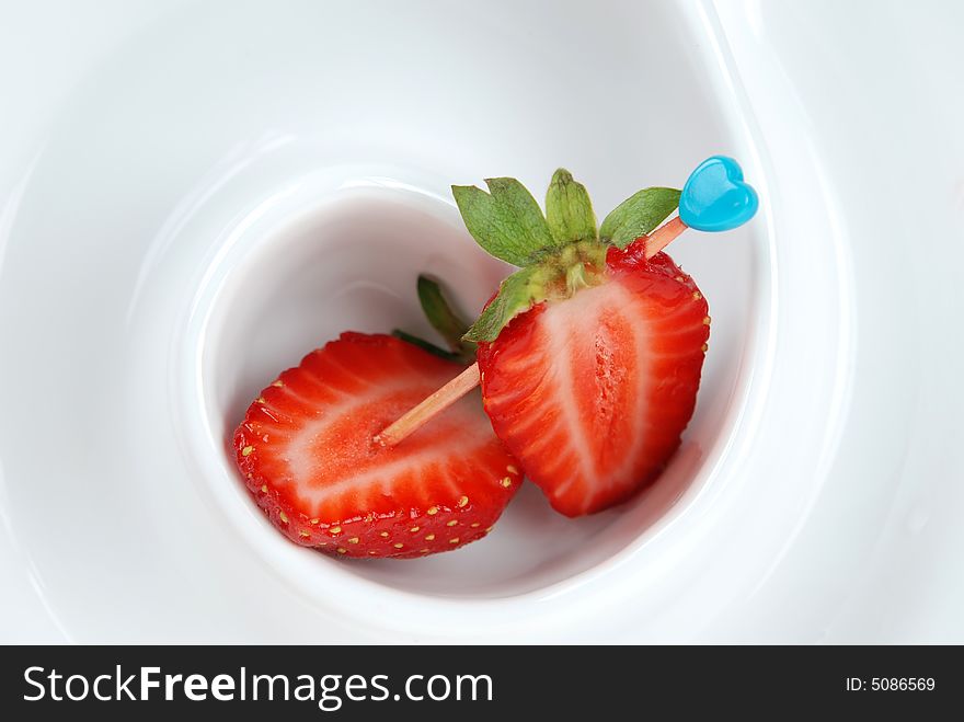 Fresh cut Strawberry in spiral form ceramic bowl with heart shaped toothpick