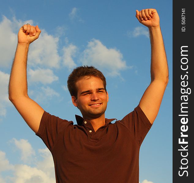 Man with his arms raised and a blue sky background. Man with his arms raised and a blue sky background.