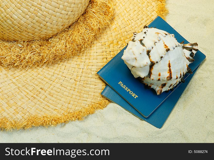 Straw hat, seashell and passports on the sand