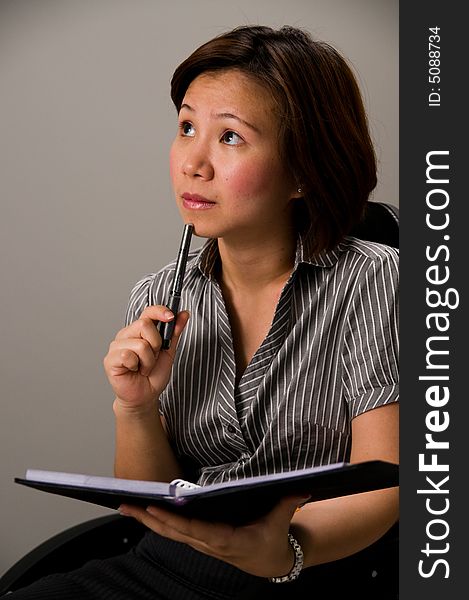 Asian lady in business attire, holding pen