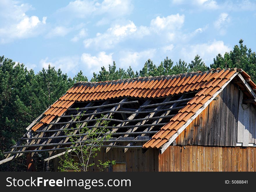 Old small house roof details over pine trees and blue sky. Old small house roof details over pine trees and blue sky