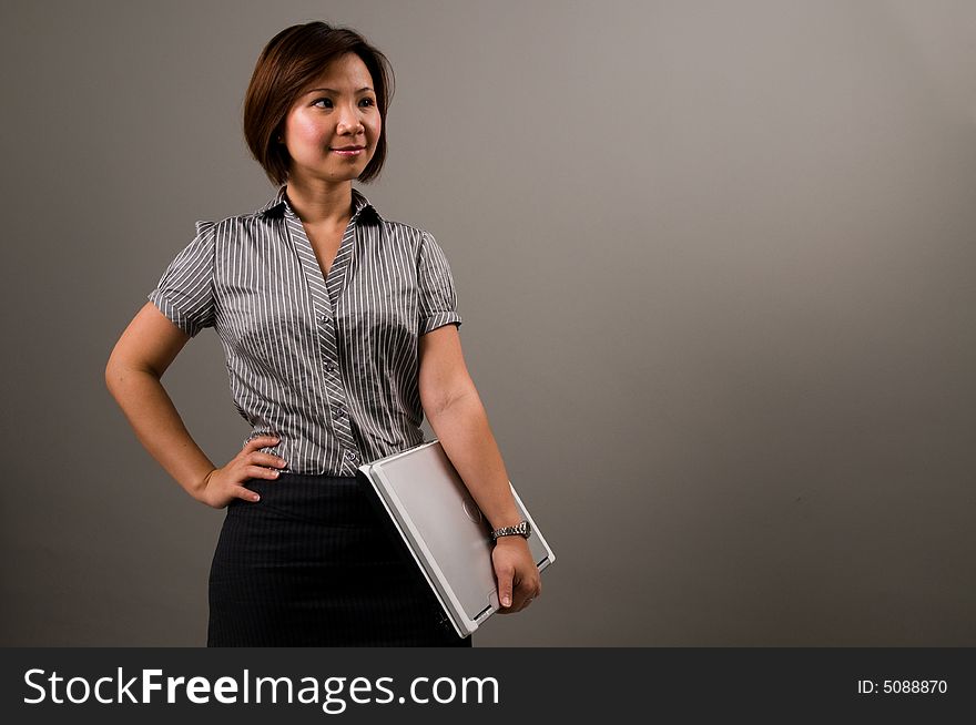 Asian lady in business attire, holding a notebook computer