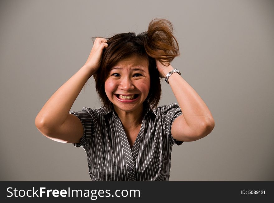 Asian lady in business attire, feeling very frustrated, tearing her hair out. Asian lady in business attire, feeling very frustrated, tearing her hair out