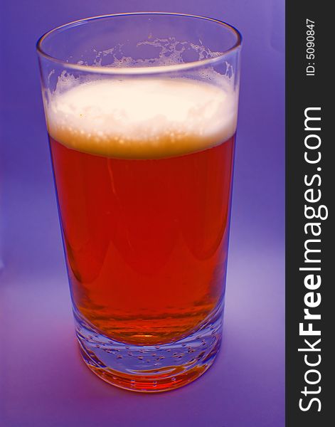 A glass of beer with purple background. A glass of beer with purple background