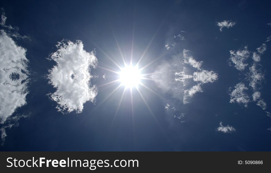 Blazing hot sun shining in blue sky with clouds