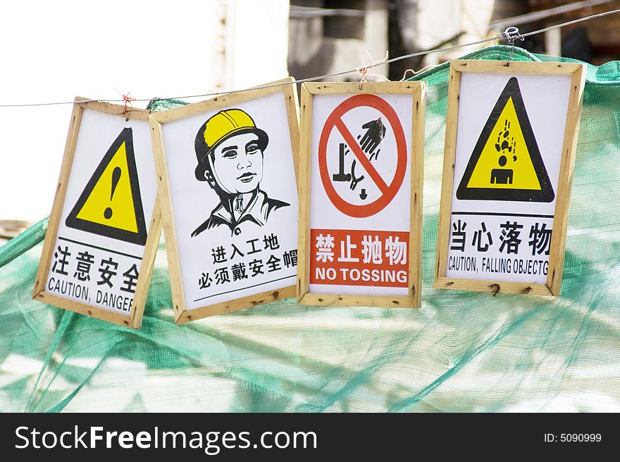 Various signs in English and Chinese to pay attention to a dangerous zone nearby a construction site. Various signs in English and Chinese to pay attention to a dangerous zone nearby a construction site.