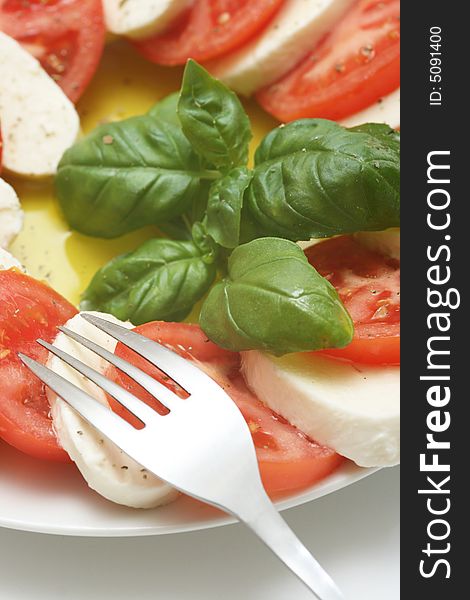 Close up of mozzarella tricolore salad with tomatoes and basil with drizzling of olive oil. Close up of mozzarella tricolore salad with tomatoes and basil with drizzling of olive oil.