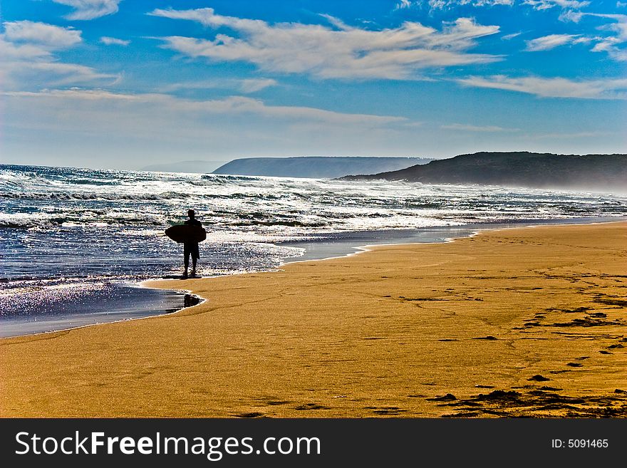 Surfer walking on a beach with a surf board