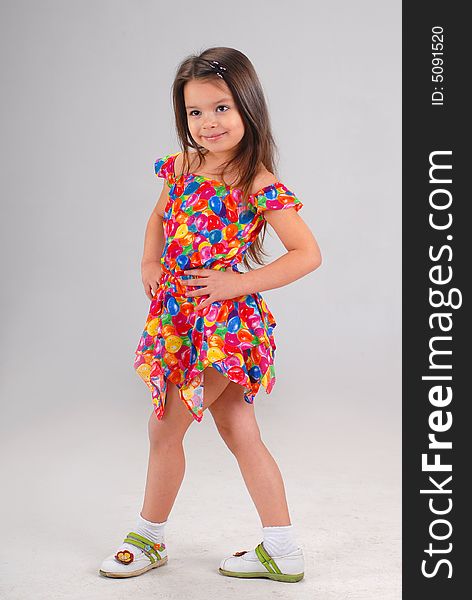 Little cute brown-haired baby girl posing in fancy-colored short dress. Little cute brown-haired baby girl posing in fancy-colored short dress