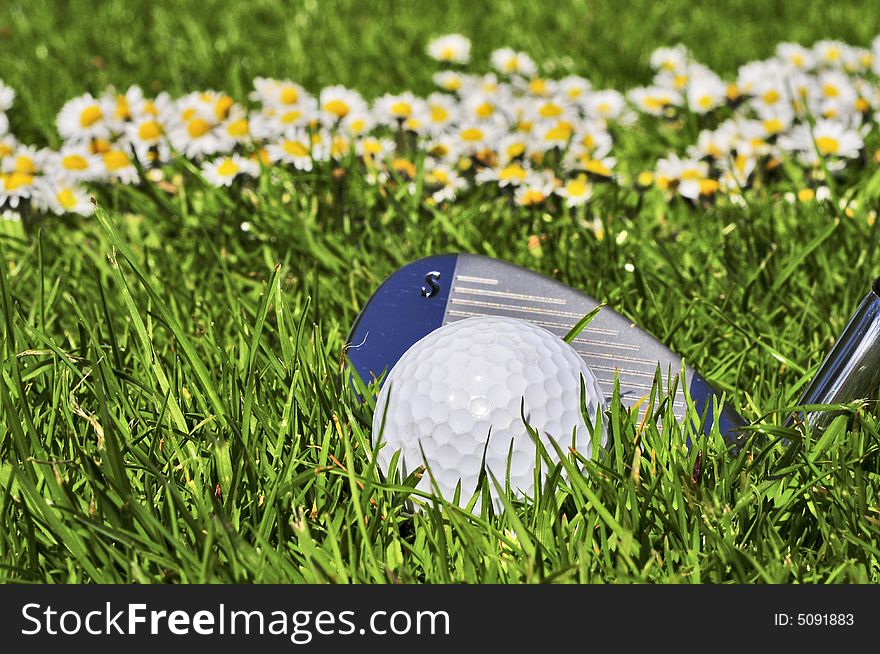 Pitching wedge and ball with flowers as background. Pitching wedge and ball with flowers as background