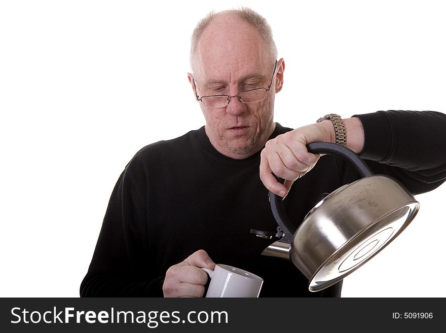 An older guy in a black shirt and glasses pouring hot water into a tea mug. An older guy in a black shirt and glasses pouring hot water into a tea mug