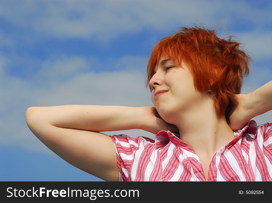 Smiling woman with red hair on blue sky background