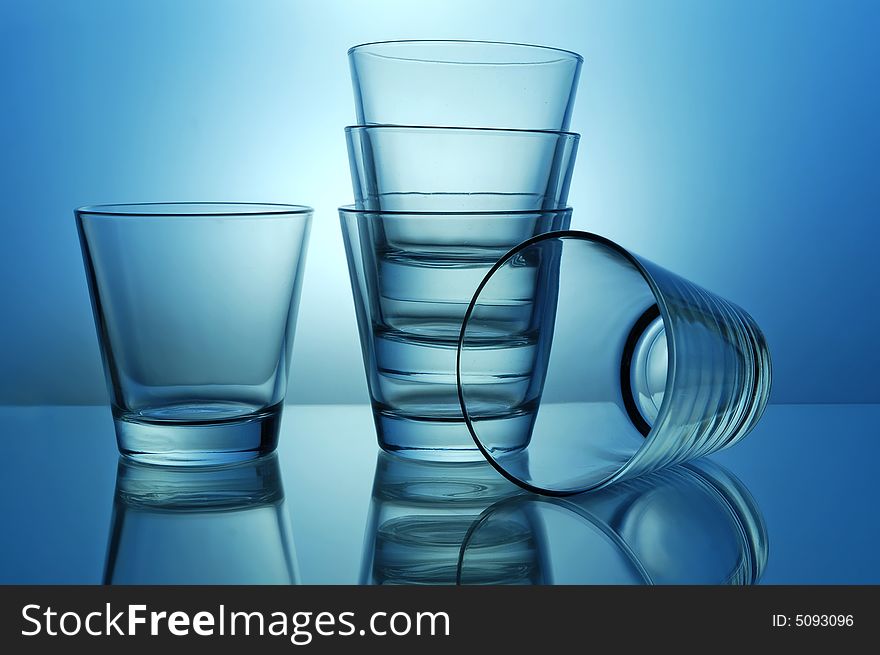 Stack of empty shots for tequila or juice on blue background. Stack of empty shots for tequila or juice on blue background