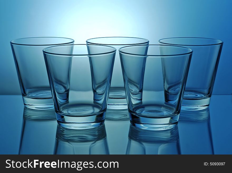 Group of empty shots for tequila or juice on blue background. Group of empty shots for tequila or juice on blue background