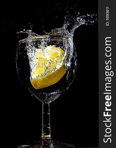 Piece of lemon falling in a glass making a big splash. Piece of lemon falling in a glass making a big splash